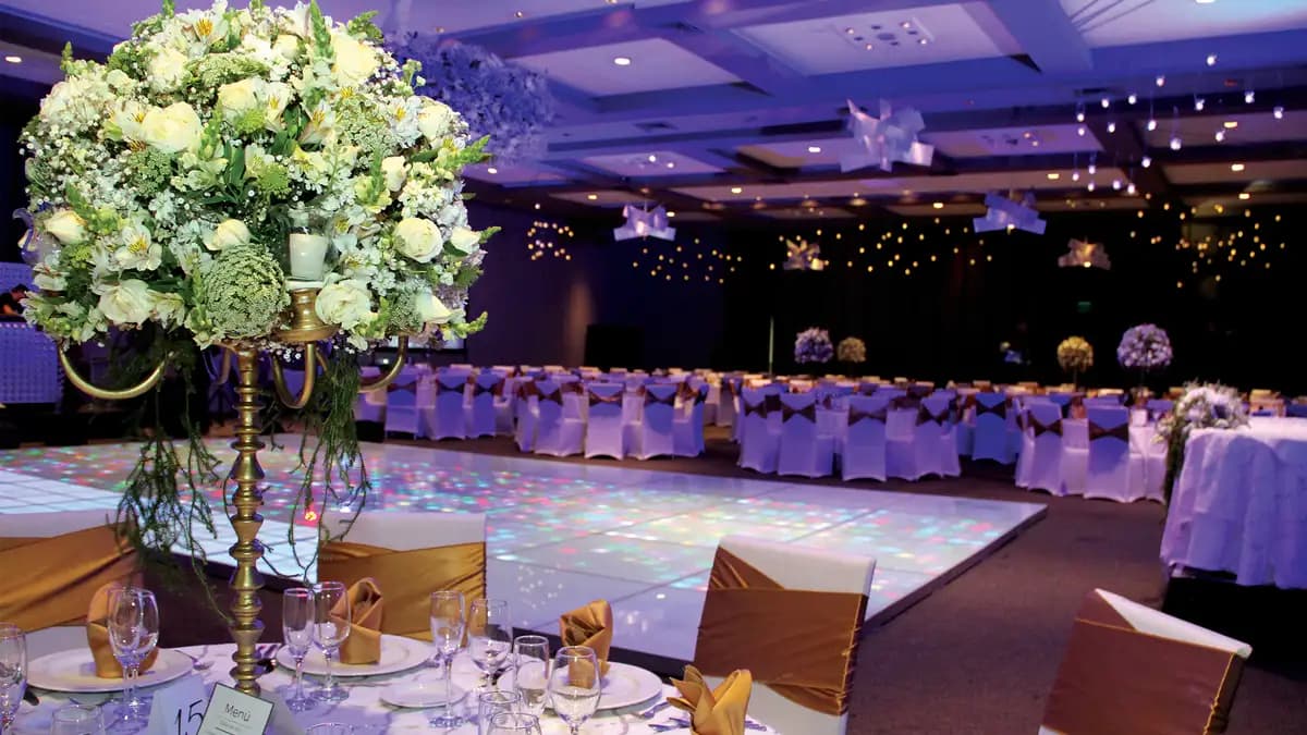 Salón Navia del Asturiano Polanco. Mesas circulares con centros de mesa y luces. Se ve centro de mesa de flor grandes.